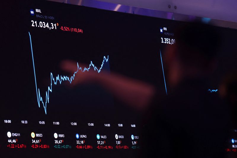 &copy; Reuters. Pessoa aponta para um painel eletrônico que exibe informações sobre as recentes flutuações dos índices de mercado na B3, em São Paulon05/08/2024nREUTERS/Carla Carniel