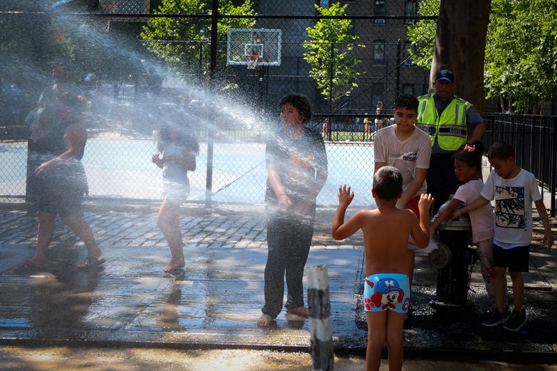 &copy; Reuters. Pessoas se refrescam com água de hidrante no bairro de Washington Heights, na região norte de Manhattan, em Nova York, EUAn24/06/2025nREUTERS/Mike Segar