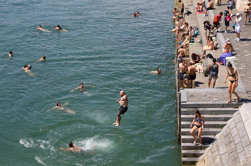 &copy; Reuters. Homem pula no rio Reno durante onda de calor, em Basileia, Suíçan02/07/2025nREUTERS/Bernadett Szabo