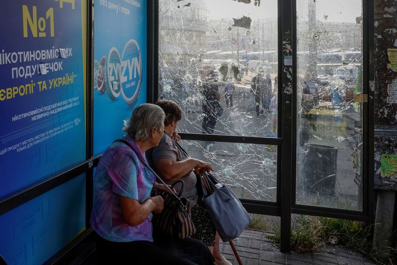 &copy; Reuters. FILE PHOTO: Women sit at a bus stop damaged during Russian drone and missile strikes, amid Russia’s attack on Ukraine, in Kyiv, Ukraine July 10, 2025. REUTERS/Alina Smutko/File Photo