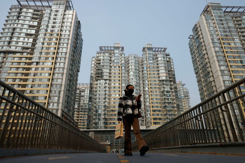 Â© Reuters. A woman walks on an overpass near residential buildings in Beijing, China March 9, 2025. REUTERS/Tingshu Wang/File Photo