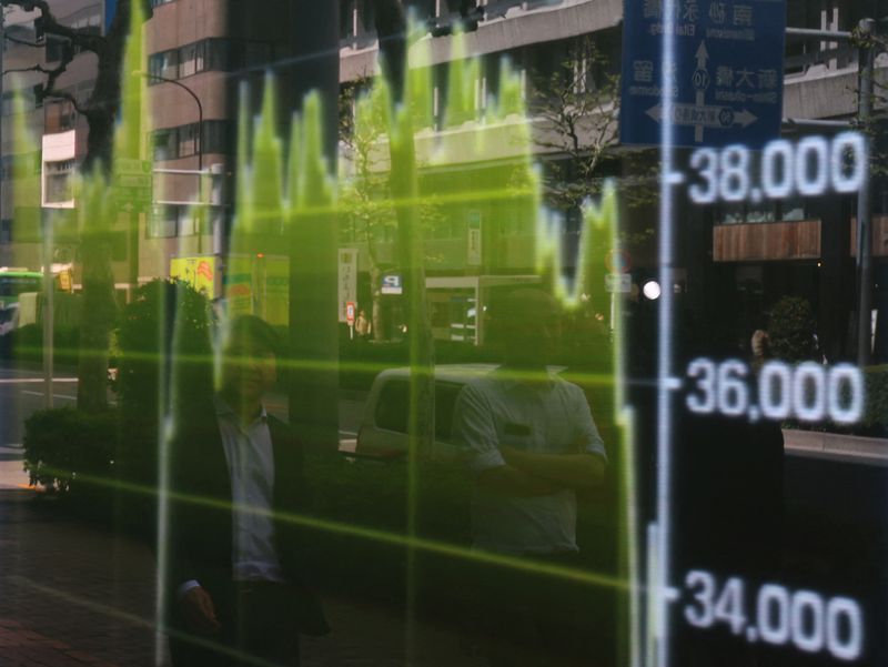 &copy; Reuters. Pedestrians are reflected on a stock quotation board showing a graph of Nikkei share average outside a brokerage in Tokyo, Japan April 14, 2025. REUTERS/Kim Kyung-Hoon/File Photo
