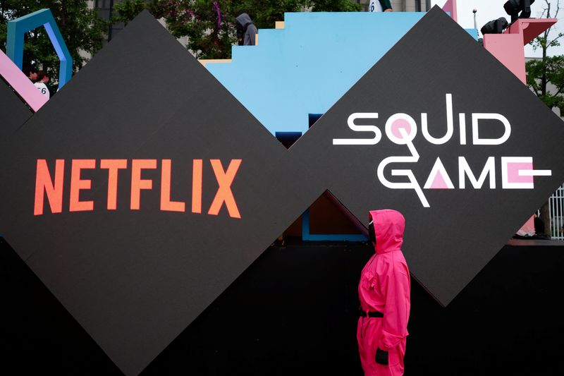 &copy; Reuters. Pessoa vestida como um soldado de "Round 6" fica em frente aos logotipos da Netflix e de "Round 6" antes de um desfile pelo centro de Seuln28/06/2025nREUTERS/Kim Soo-hyeon