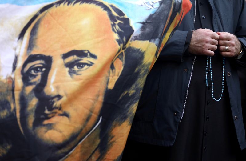 &copy; Reuters. Padre segura terço ao lado de bandeira com o retrato do falecido ditador espanhol Francisco Franco, do lado de fora do cemitério Mingorrubio-El Pardo, em Madri, Espanhan24/10/2019nREUTERS/Sergio Perez