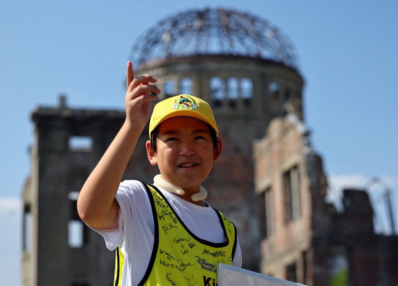 &copy; Reuters. Shun Sasaki, estudante do ensino fundamental na cidade japonesa de Hiroshima, guia turistas em frente ao Domo da Bomba Atômica em Hiroshiman15/07/2025 REUTERS/Issei Kato