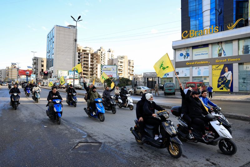 &copy; Reuters. Homens carregam bandeiras do Hezbollah enquanto andam de moto, na entrada dos subúrbios ao sul de Beiruten27/11/2024nREUTERS/Thaier Al-Sudani