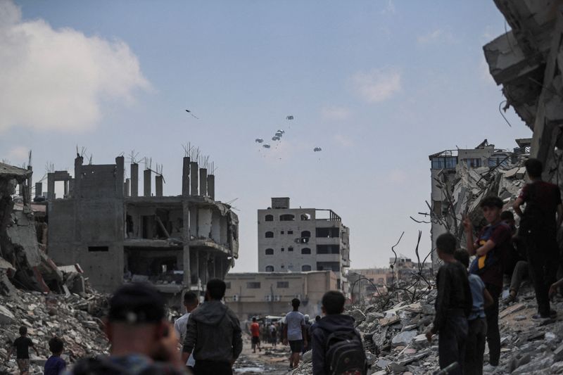 &copy; Reuters. FILE PHOTO: Palestinians look at aid packages that are airdropped over Gaza, in Gaza City, August 8, 2025. REUTERS/Mahmoud Issa/File Photo