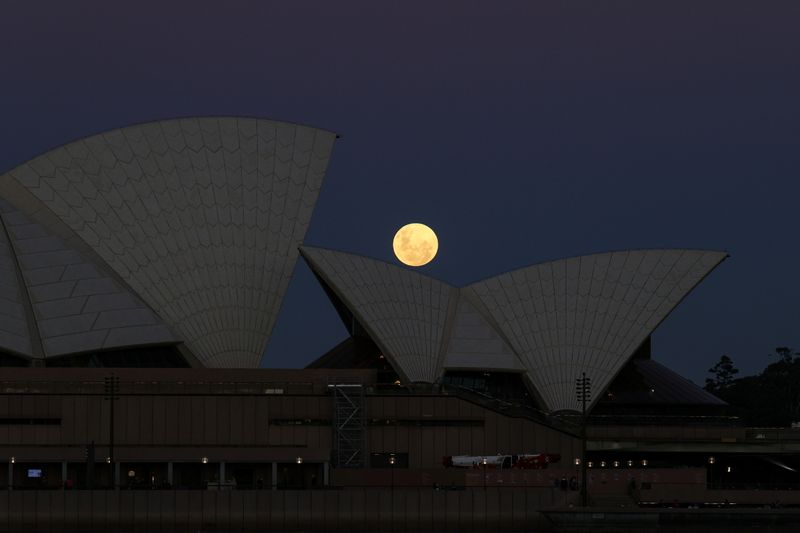 © Reuters. A Super Flower Moon rises behind the Sydney Opera House on the night of a lunar eclipse, in Sydney, Australia, May 26, 2021.  REUTERS/Loren Elliott