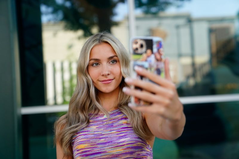 © Reuters. Katie Feeney, an 18-year-old social media personality, poses with her phone at a shopping center where she films many of her videos, in Gaithersburg, Maryland, U.S., May 25, 2021. REUTERS/Erin Scott