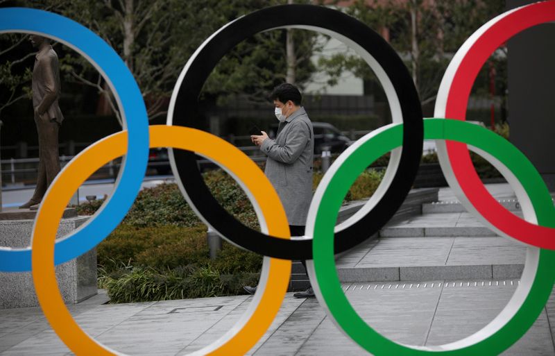 &copy; Reuters. رجل يضع كمامة للوقاية من فيروس كورونا ويظهر خلف حلقات أولمبية عملاقة في طوكيو بصورة من أرشيف رويترز.