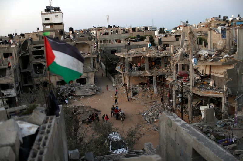 © Reuters. علم فلسطين يرفرف بالقرب من حطام منازل في قطاع غزة يوم الثلاثاء دمرتها ضربات جوية اسرائيلية. تصوير: محمد سالم-رويترز.
