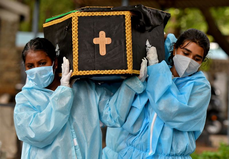 &copy; Reuters. Volunteers, Akshaya (R), 22, a law student, and Esther Mary, 41, a lecturer, carry the body of a person who died from the coronavirus disease (COVID-19) for burial at a cemetery in Bengaluru, India, May 18, 2021. REUTERS/Samuel Rajkumar/File Photo