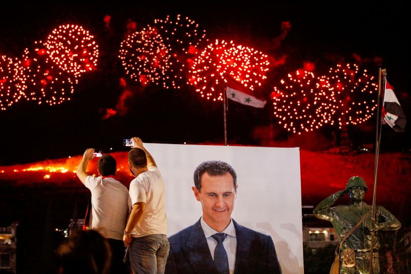 &copy; Reuters. A poster depicting Syria’s president Bashar al- Assad is seen as supporters of him celebrate after the results of the presidential election announced that he won a fourth term in office, in Damascus, Syria, May 27, 2021. REUTERS/Omar Sanadiki     TPX IM
