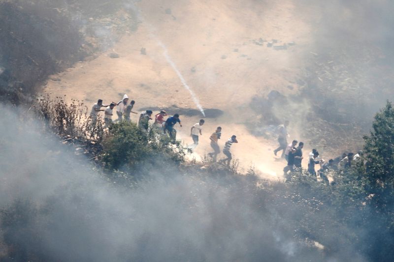 &copy; Reuters. متظاهرون فلسطينيون يحاولون الهرب من الغاز المسيل للدموع الذي أطلقه جنود إسرائيليون في الضفة الغربية يوم الجمعة. تصوير: رنين صوافطة - رويترز.