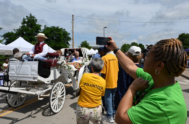 &copy; Reuters. People wave and a woman stops to photograph the longest living known survivors of the Tulsa Race Massacre at the 2021 Black Wall Street Legacy Festival in Tulsa, Oklahoma, U.S., May 28, 2021. 