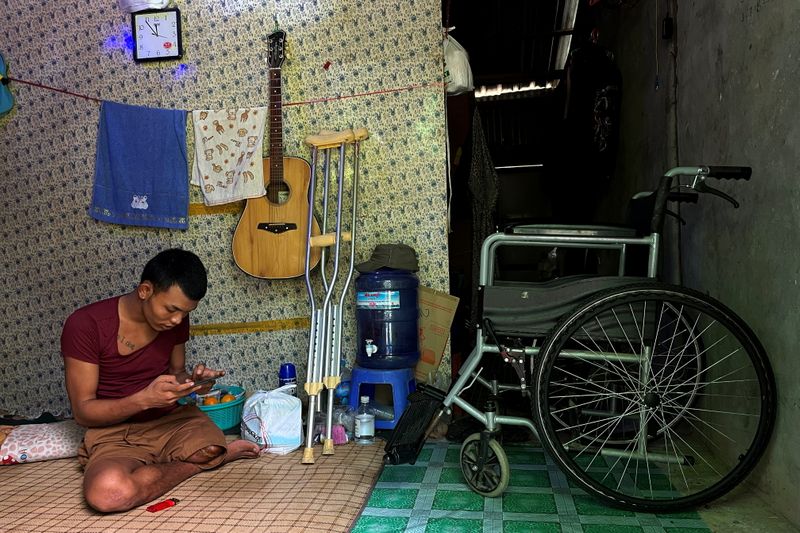 &copy; Reuters. Ko Phyo, 24, a protester who lost one leg during an anti-coup protest, plays a video game with his mobile phone at his home on the outskirts of Yangon, Myanmar, May 4, 2021.REUTERS/Stringer   