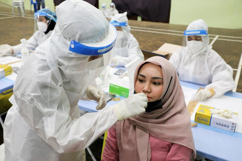 &copy; Reuters. FILE PHOTO: A medical worker collects a swab sample from a woman to be tested for the coronavirus disease (COVID-19) in Kuala Lumpur, Malaysia, May 11, 2021. REUTERS/Lim Huey Teng