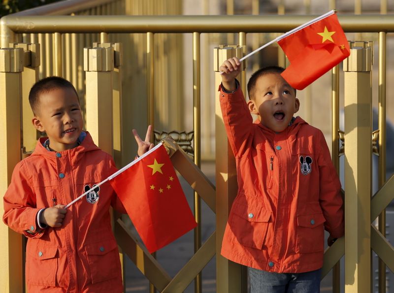 &copy; Reuters. Twin boys Sun Qiyu and Sun Qichun hold China's national flags on the Tiananmen Gate in Beijing November 2, 2015. China must continue to enforce its one-child policy until new rules allowing all couples to have two children go into effect, the top family p