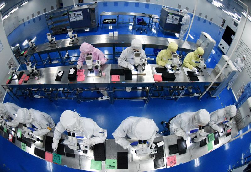 &copy; Reuters. FILE PHOTO: Employees work on a production line manufacturing camera lenses for cellphones at a factory in Lianyungang, Jiangsu province, China April 30, 2019. Picture taken with a fisheye lens. China Daily via REUTERS