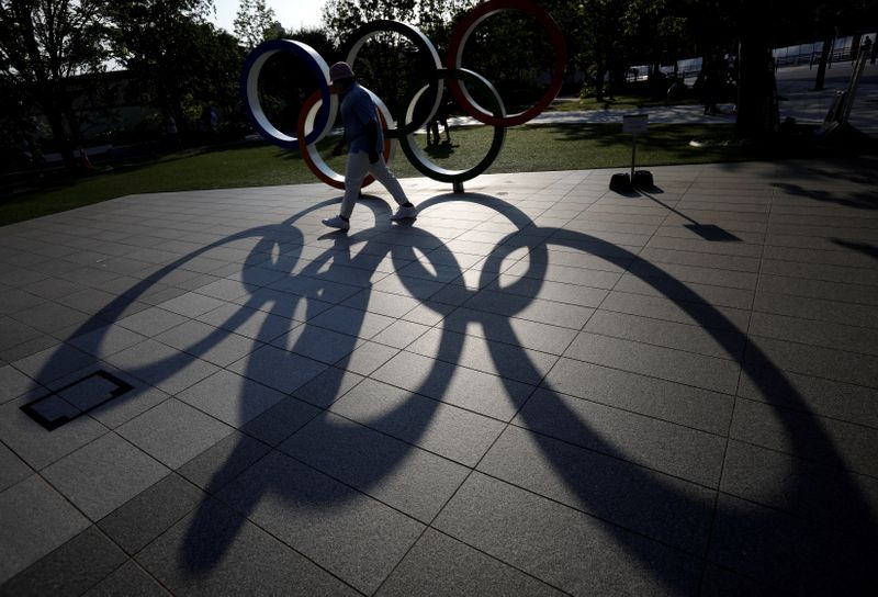 &copy; Reuters. FILE PHOTO: A visitor and the Olympic Rings monument cast shadows on the ground outside the Japan Olympic Committee (JOC) headquarters near the National Stadium, the main stadium for the 2020 Tokyo Olympic Games that have been postponed to 2021 due to the