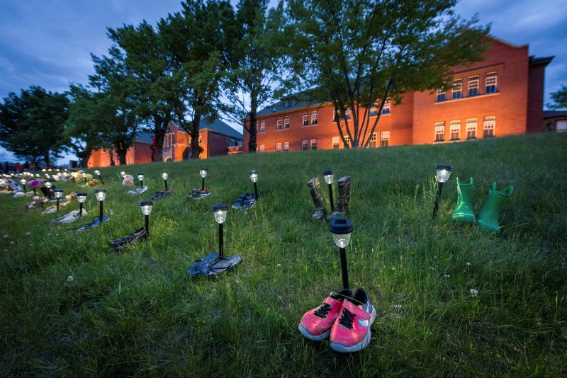 © Reuters. Pairs of children's shoes and toys are seen at memorial in front of the former Kamloops Indian Residential School after the remains of 215 children, some as young as three years old, were found at the site last week, in Kamloops, British Columbia, Canada May 31, 2021. REUTERS/Dennis Owen