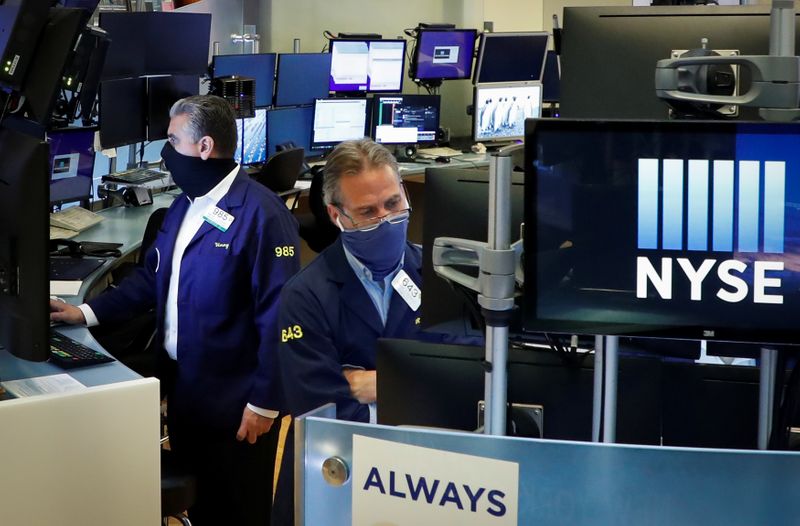 © Reuters. Traders wearing masks work, on the first day of in person trading since the closure during the outbreak of the coronavirus disease (COVID-19) on the floor at the New York Stock Exchange (NYSE) in New York, U.S., May 26, 2020. REUTERS/Brendan McDermid/Files
