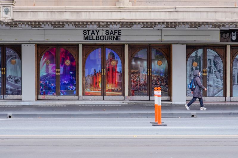 &copy; Reuters. FILE PHOTO: A woman walks past a "Stay Safe Melbourne" sign on a mostly-empty city centre street on the first day of a seven-day lockdown as the state of Victoria looks to curb the spread of a coronavirus disease (COVID-19) outbreak, in Melbourne, Austral