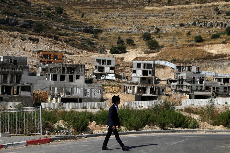 © Reuters. FILE PHOTO: A Jewish settler walks past Israeli settlement construction sites around Givat Zeev and Ramat Givat Zeev in the Israeli-occupied West Bank, near Jerusalem June 30, 2020. REUTERS/Ammar Awad     TPX IMAGES OF THE DAY/File Photo