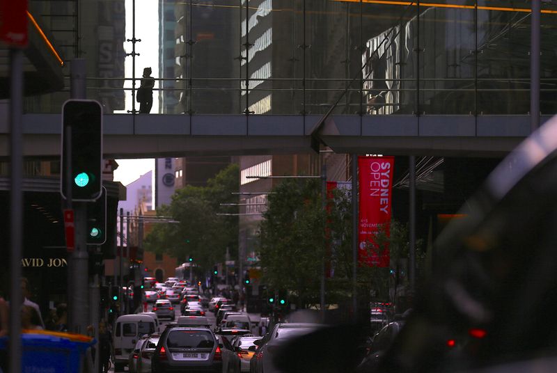 &copy; Reuters. FILE PHOTO: Cars drive along a main road as a shopper walks across a pedestrian bridge connecting retail stores in central Sydney, Australia, October 27, 2017. REUTERS/Steven Saphore