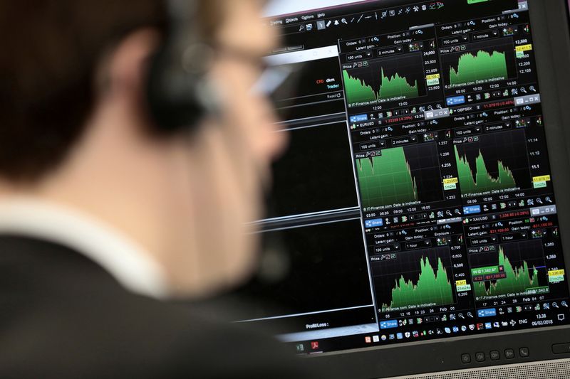 © Reuters. FILE PHOTO: A broker looks at financial information on computer screens on the IG Index the trading floor in London, Britain February 6, 2018. REUTERS/Simon Dawson/File Photo