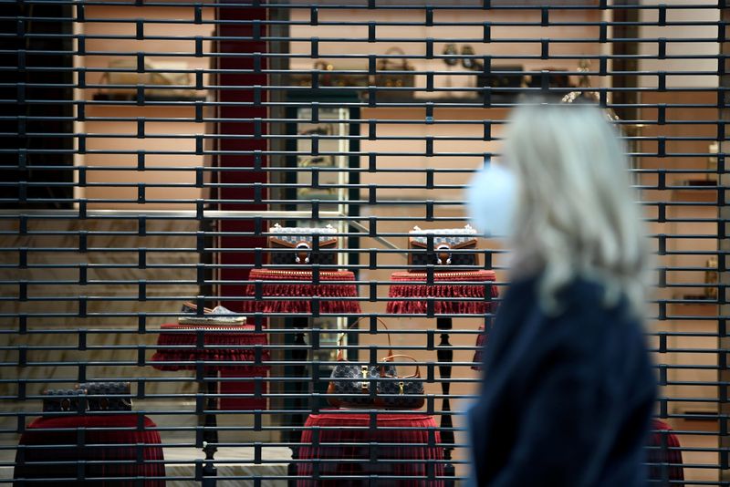 &copy; Reuters. FILE PHOTO: A woman wearing a protective face mask walks past a closed shop as the region of Lombardy becomes a 'red zone', going into lockdown as the country struggles to reduce the coronavirus disease (COVID-19) infections, in Milan, Italy, March 15, 20