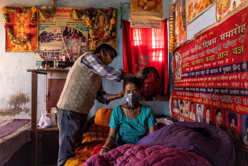 &copy; Reuters. FILE PHOTO: Suresh Kumar, 43, ties up the hair of his wife Pramila Devi, 36, who is suffering from the coronavirus disease (COVID-19), before taking her to a local government dispensary, at their home in Kaljikhal, in the northern state of Uttarakhand,