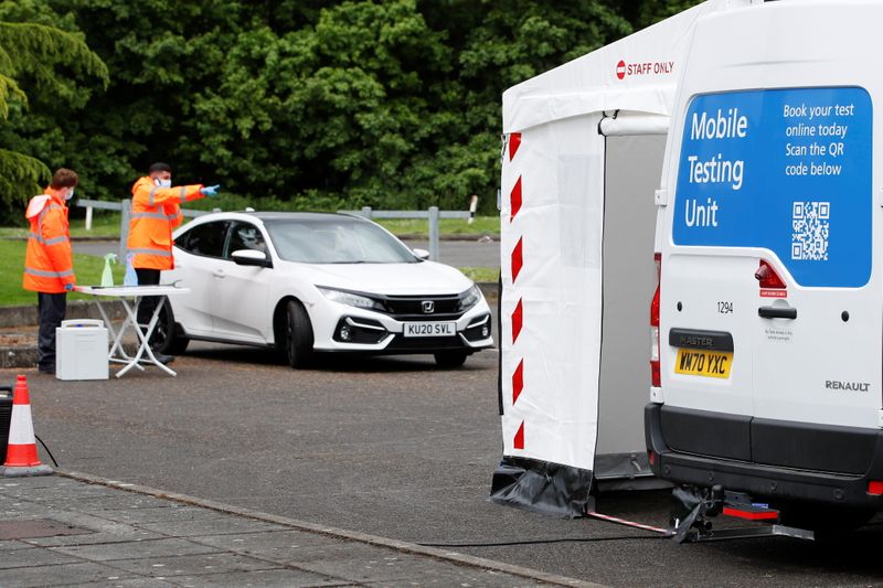 &copy; Reuters. Staff members stand next to a car at a coronavirus disease (COVID-19) mobile testing unit at Oasis Beach Swimming Pool in Bedford, Britain May 25, 2021. REUTERS/Paul Childs