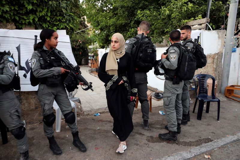 © Reuters. Prominent Palestinian activist Muna El-Kurd walks by Israeli border police, out from the courtyard of her house in the East Jerusalem neighbourhood of Sheikh Jarrah, June 6, 2021. REUTERS/Ammar Awad