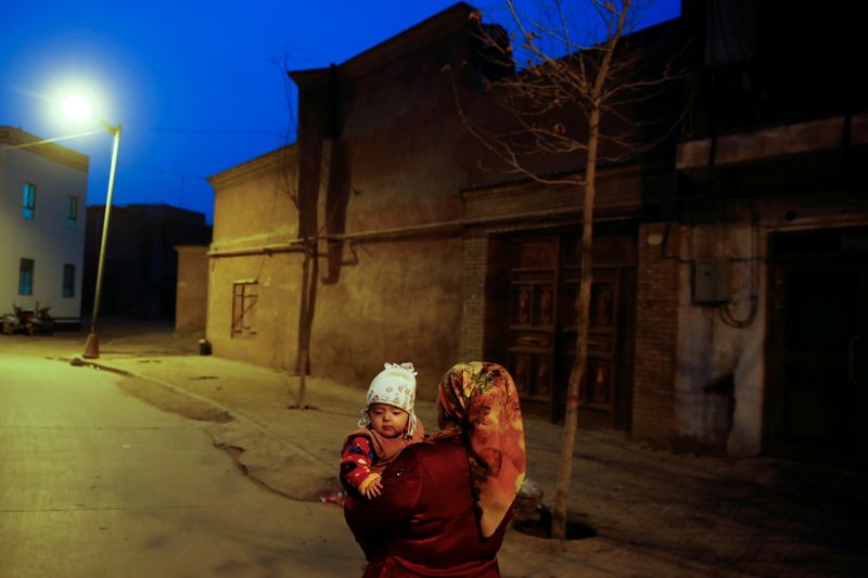 &copy; Reuters. FILE PHOTO: A woman carries a child at night in the old town of Kashgar, Xinjiang Uighur Autonomous Region, China, March 23, 2017.  REUTERS/Thomas Peter/File Photo