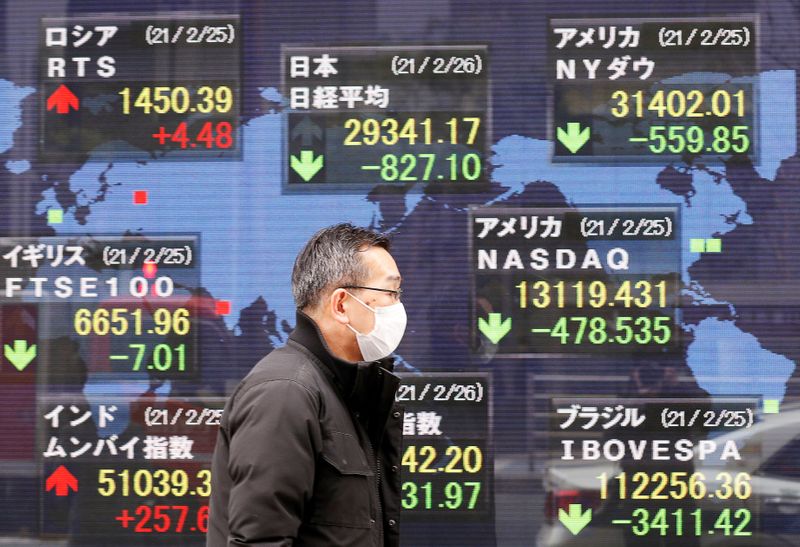 &copy; Reuters. رجل يضع كمامة للوقاية من فيروس كورونا يسير أمام لوحة إلكترونية تعرض مؤشرات الأسواق في طوكيو يوم 26 فبراير شباط 2021. تصوير: كيم كيونج هون - رويتر