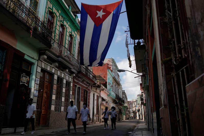 &copy; Reuters. FILE PHOTO: Medical students walk past a Cuban flag as they check door-to-door for people with symptoms amid concerns about the spread of the coronavirus disease (COVID-19), in downtown Havana, Cuba, May 12, 2020. REUTERS/Alexandre Meneghini