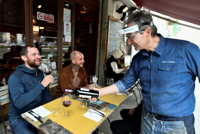&copy; Reuters. Un camiere serve del vino a un cliente presso un ristorante sul canale dei Navigli a Milano. REUTERS/Flavio Lo Scalzo