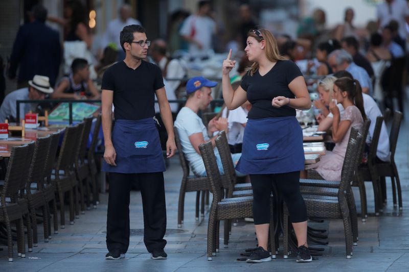 &copy; Reuters. Una camarera y un camarero charlan mientras esperan a los clientes en la terraza de un restaurante en el centro de Ronda, sur de España 31 de agosto de 2018. REUTERS/Jon Nazca - RC151BF579C0