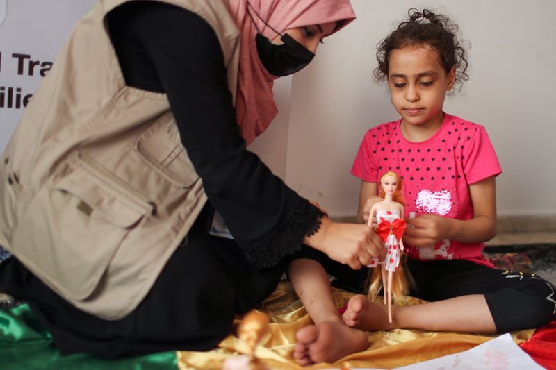 &copy; Reuters. طبيبة نفسية تلعب مع سوزي اشكنتنا في غزة في الثالث من يونيو حزيران 2021. تصوير: محمد سالم - رويترز