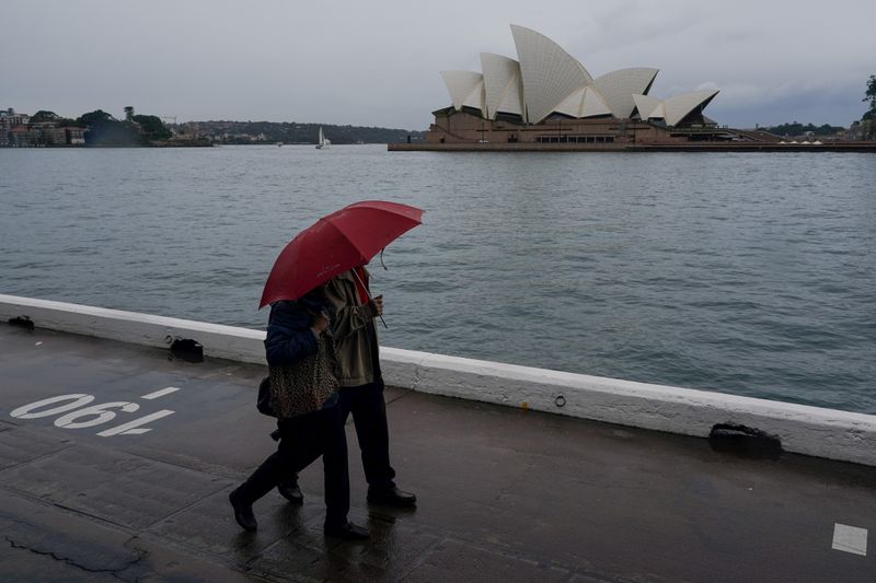 &copy; Reuters. شخصان يتشاركان مظلة في سيدني بينما يواجه سكان شرق أستراليا موجة طقس شتوي قارس وسيول يوم الخميس. تصوير: لورين إليوت - رويترز.