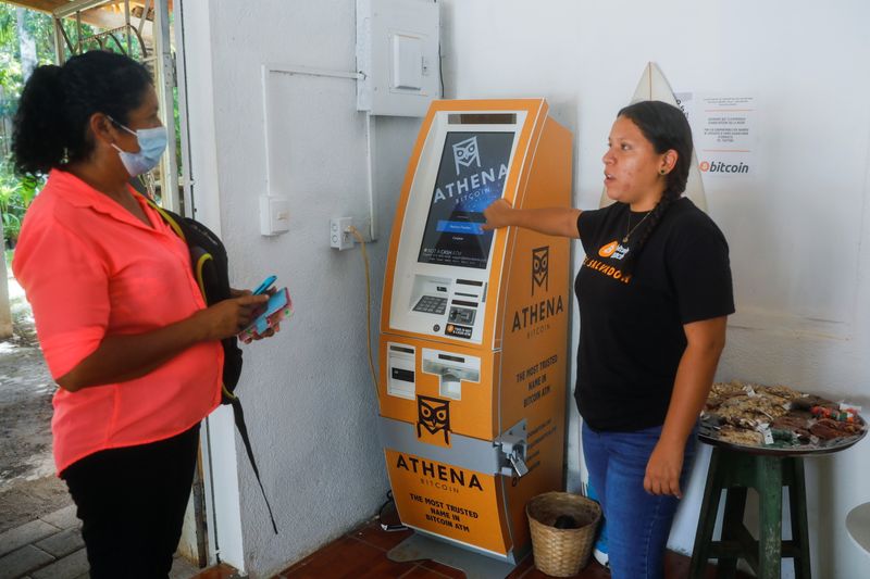 &copy; Reuters. An employee at a Bitcoin support office explains how to make a transaction to a woman at El Zonte Beach in Chiltiupan, El Salvador June 8, 2021. REUTERS/Jose Cabezas
