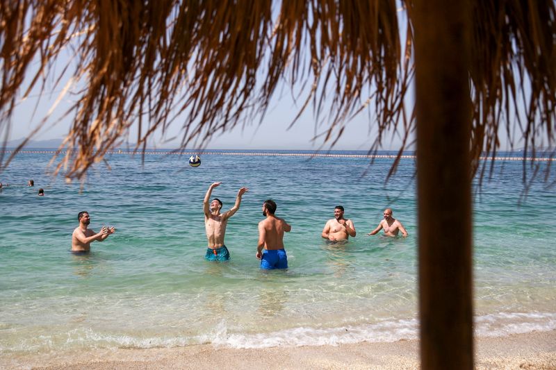 &copy; Reuters. FILE PHOTO: People enjoy the sea during the official reopening of beaches to the public, following the easing of measures against the spread of the coronavirus disease (COVID-19), in Athens, Greece, May 8, 2021. REUTERS/Costas Baltas/File Photo
