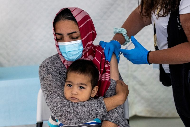 &copy; Reuters. FOTO DE ARCHIVO: Una migrante sostiene a su bebé mientras recibe una inyección de la vacuna Johnson & Johnson contra el COVID-19 en el campamento de Mavrovouni para refugiados y migrantes en la isla de Lesbos, Grecia REUTERS/Alkis Konstantinidis