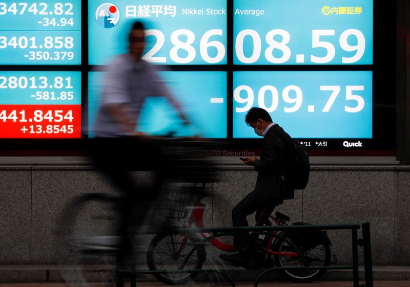 &copy; Reuters. People ride bicycles past a screen displaying Nikkei share average outside a brokerage, amid the coronavirus disease (COVID-19) outbreak, in Tokyo, Japan May 11, 2021. REUTERS/Issei Kato