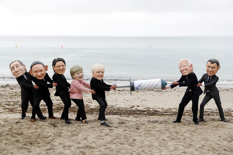 © Reuters. Oxfam activists with 'Big Heads' caricatures of U.S. President Joe Biden and France's President Emmanuel Macron pretend to fight over a COVID-19 vaccine with other G7 leaders, during a protest at a beach near Falmouth, on the sidelines of G7 summit, in Cornwall, Britain, June 11, 2021.  REUTERS/Peter Nicholls