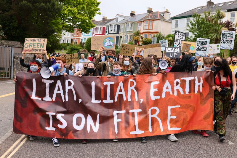 © Reuters. People hold signs during a protest of Cornwall Climate Youth Alliance in partnership with Fridays for Future and Climate Live, at Gyllyngvase Beach, in Falmouth, on the sidelines of G7 summit in Cornwall, Britain, June 11, 2021. REUTERS/Tom Nicholson