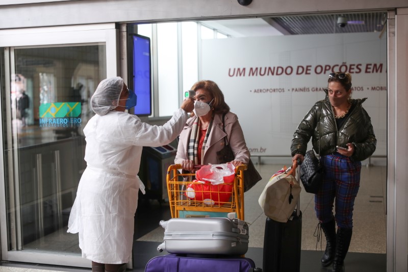 &copy; Reuters. FOTO DE ARCHIVO: Una trabajadora de salud mide la temperatura de un viajero en una barrera sanitaria cuando llega al aeropuerto de Congonhas en Sao Paulo, Brasil, el 31 de mayo de 2021. REUTERS/Amanda Perobelli