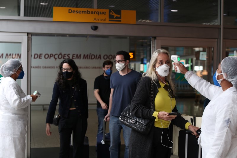 &copy; Reuters. FOTO DE ARCHIVO: Una trabajadora de salud mide la temperatura de un viajero en una barrera sanitaria mientras ella y otros llegan al aeropuerto de Congonhas en Sao Paulo, Brasil, el 31 de mayo. REUTERS/Amanda Perobelli