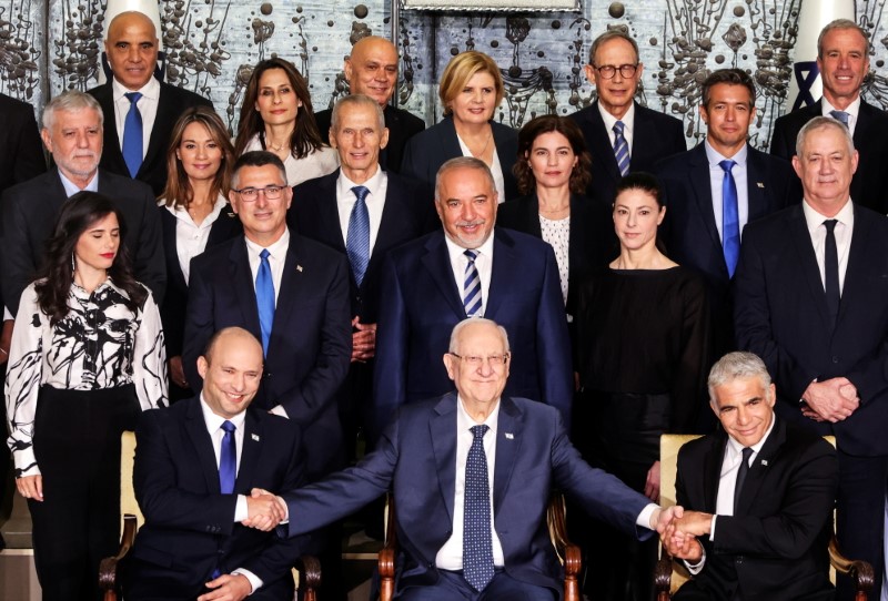 © Reuters. Israel's President Reuven Rivlin sits next to Prime Minister Naftali Bennett and Foreign Minister Yair Lapid as they pose for a group photo with ministers of the new Israeli government, in Jerusalem June 14, 2021. REUTERS/Ronen Zvulun